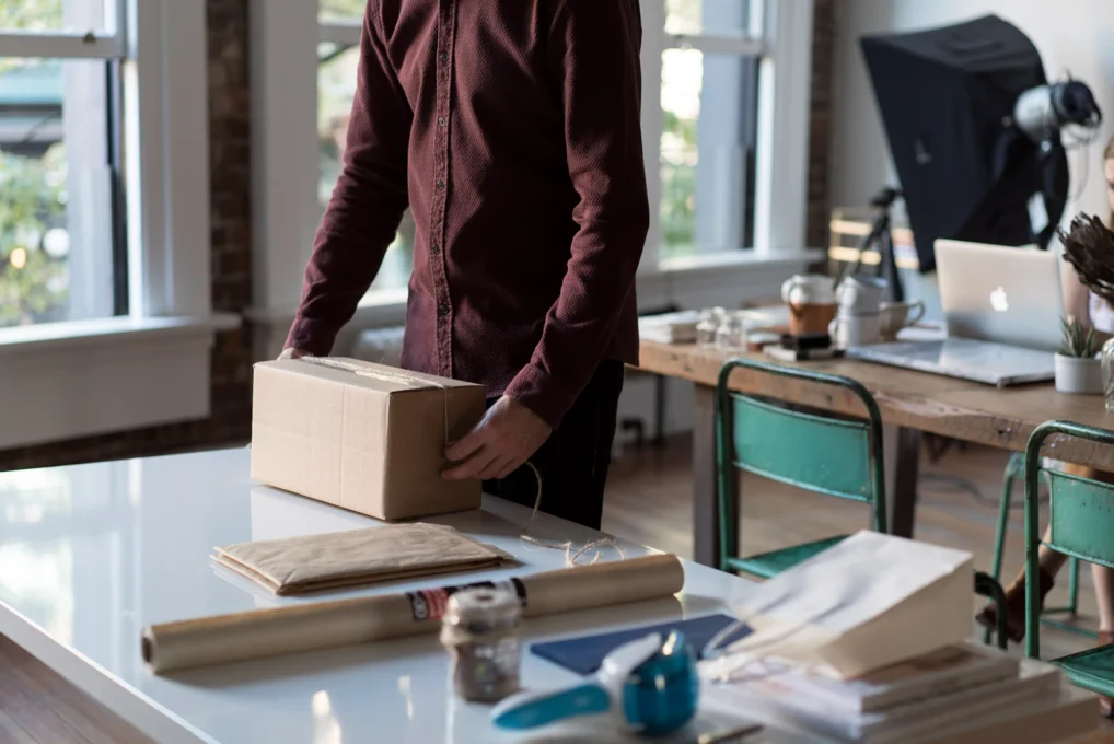 Person packing online orders into cardboard boxes