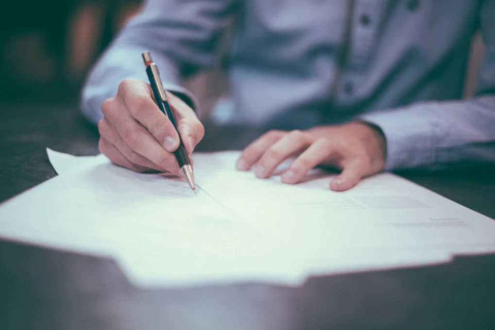 AI Writing Tools Compared: 10 Options, Features and Pricing 3 Hands reviewing and editing a printed document with a pen